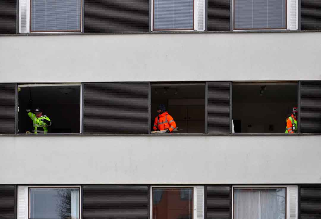 Kolme asentajaa valmistelee ikkuna-aukkoja.